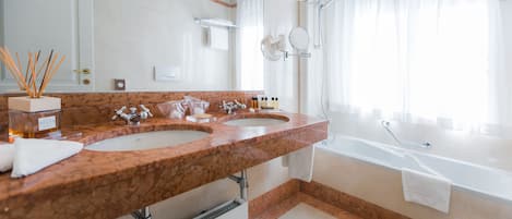 A modern bathroom with two sinks, a bathtub, and a large mirror.