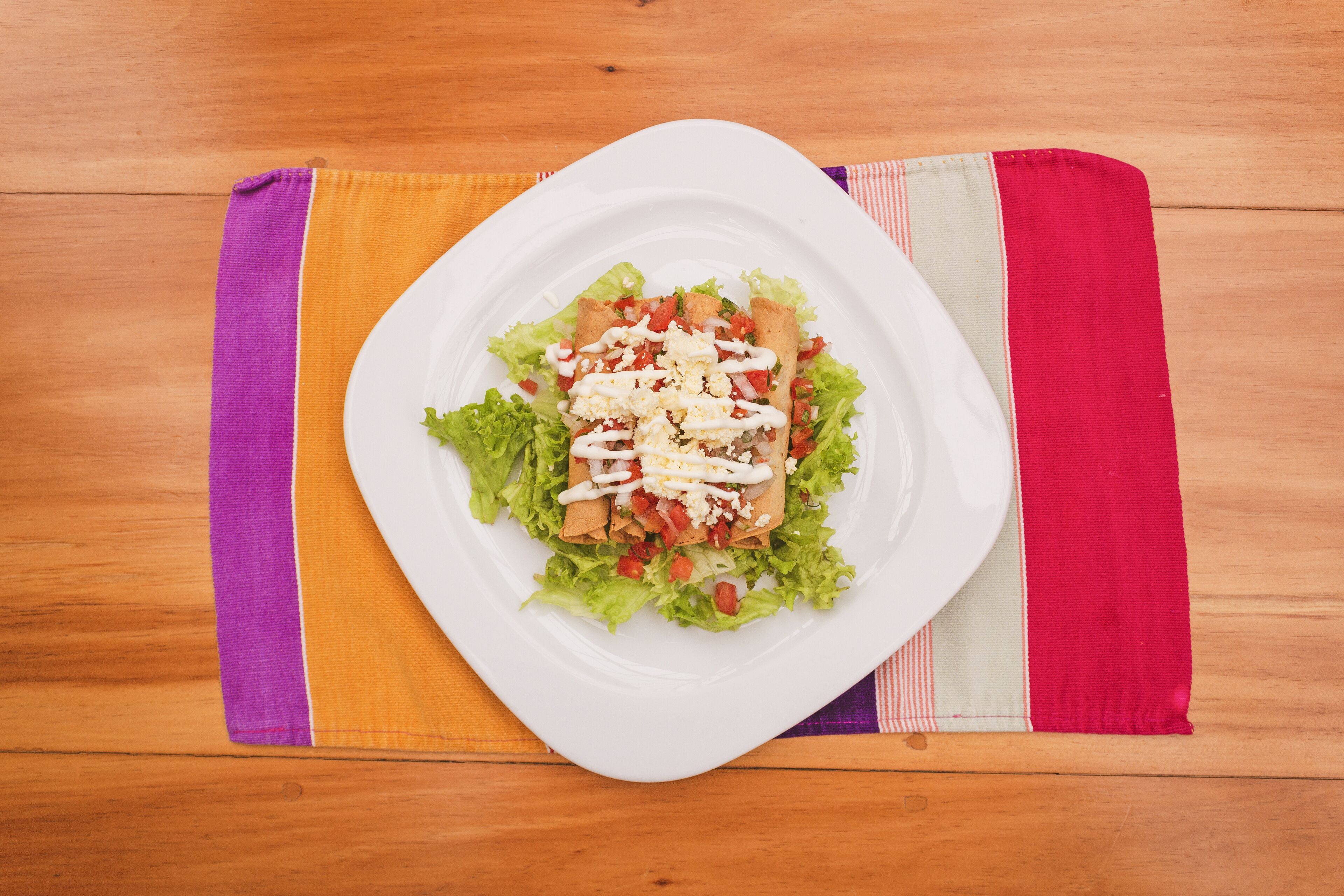 Un plato blanco con una ensalada sobre una mesa de madera.
