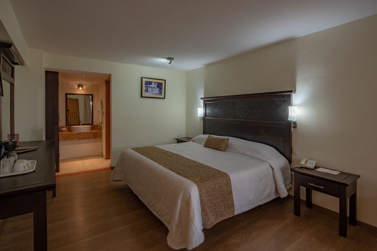 Une chambre d’hôtel comprenant un lit, une table de chevet et un bureau avec un téléphone.