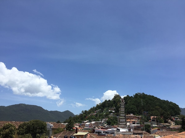 A town with a prominent tower on a hill, surrounded by residential buildings and greenery. - Hotel Plaza Magnolias (San Cristóbal de las Casas)