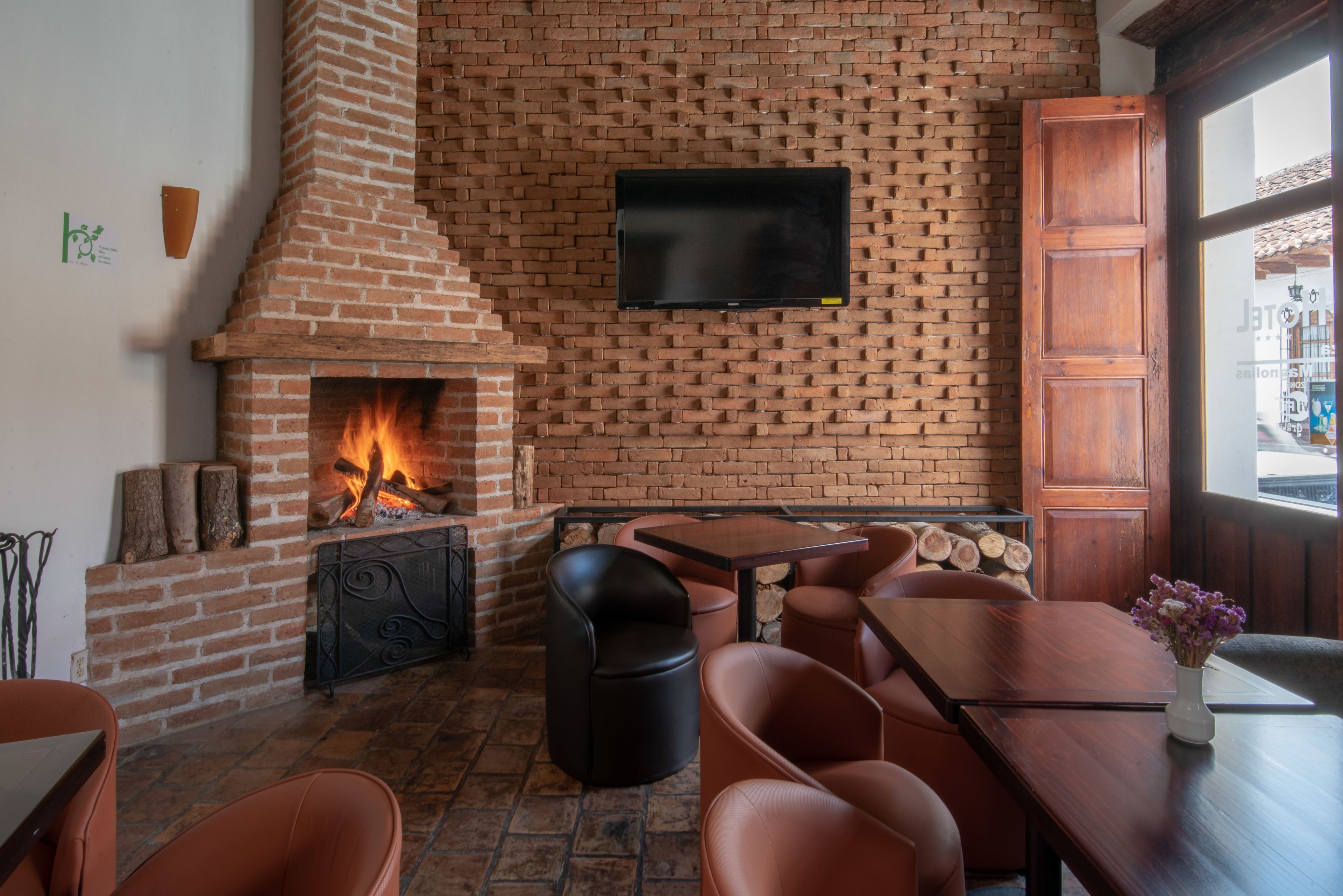 A brick fireplace with a TV mounted above it, surrounded by leather seating and a wooden table.