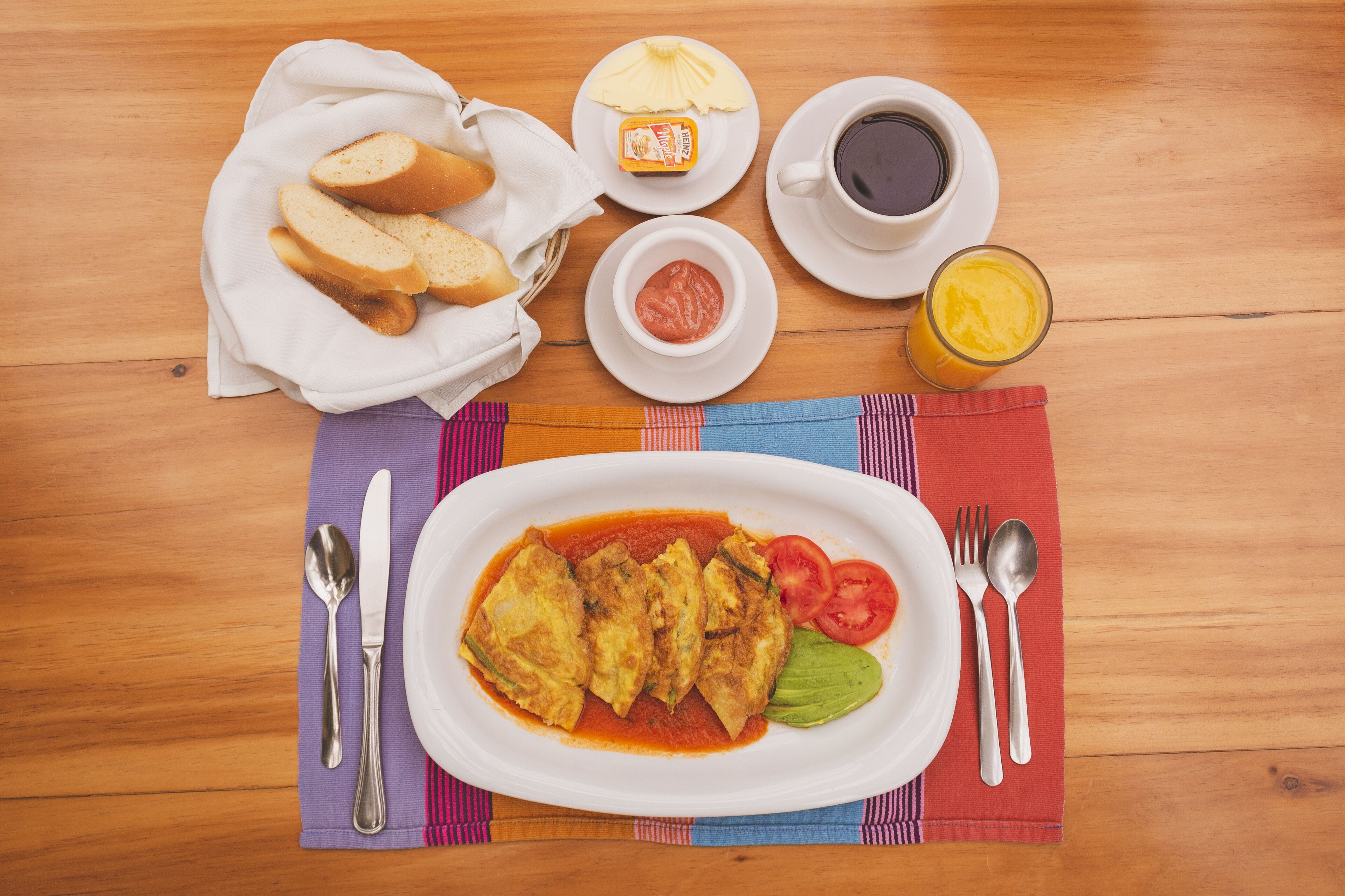A meal with bread, ketchup, and a glass of juice on a wooden table.