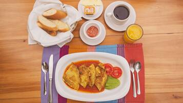 A meal with bread, ketchup, and a glass of juice on a wooden table.