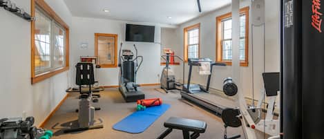 A gym with exercise equipment, a blue mat, and a bench.