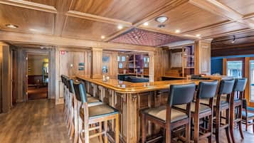 Een barruimte met houten barstoelen en een hoog plafond met inbouwverlichting.