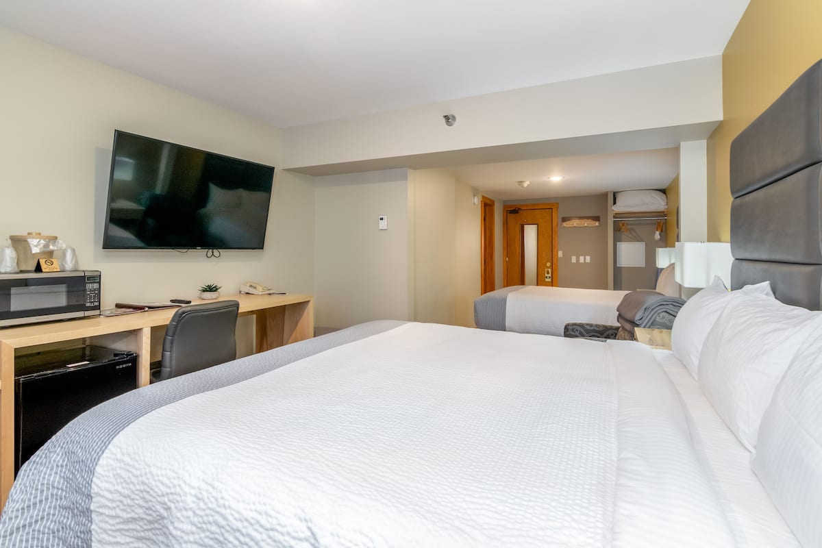 A hotel room with a large bed, a desk with a computer, a microwave, and a TV.