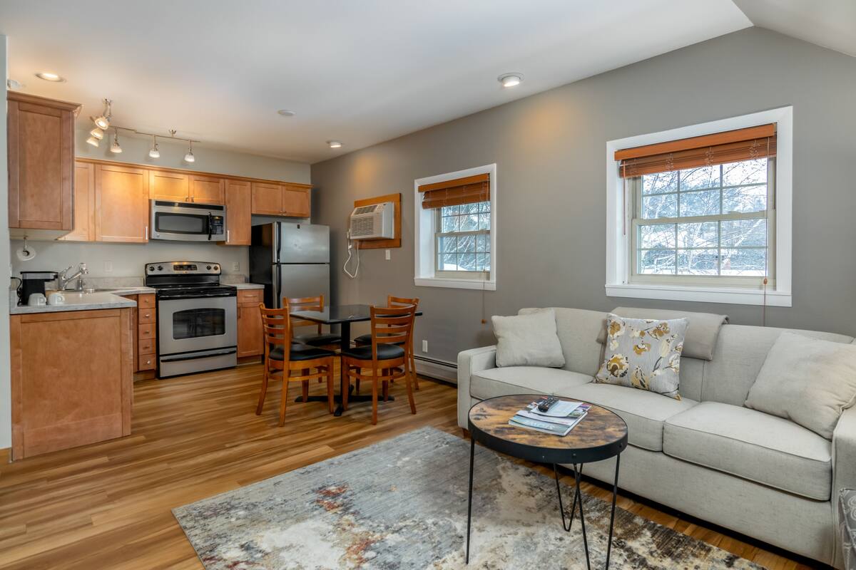 A modern kitchen with wooden cabinets, stainless steel appliances, and a dining area with a table and chairs.