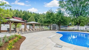 A swimming pool with lounge chairs and a gazebo.
