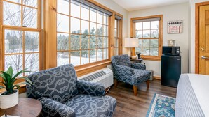 A cozy room with large windows, a heater, a TV, and a ski zone caution sign. - Grey Fox Inn (Stowe)