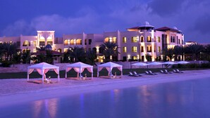Un gran resort con varias construcciones, un área de playa con tumbonas y tiendas de campaña.