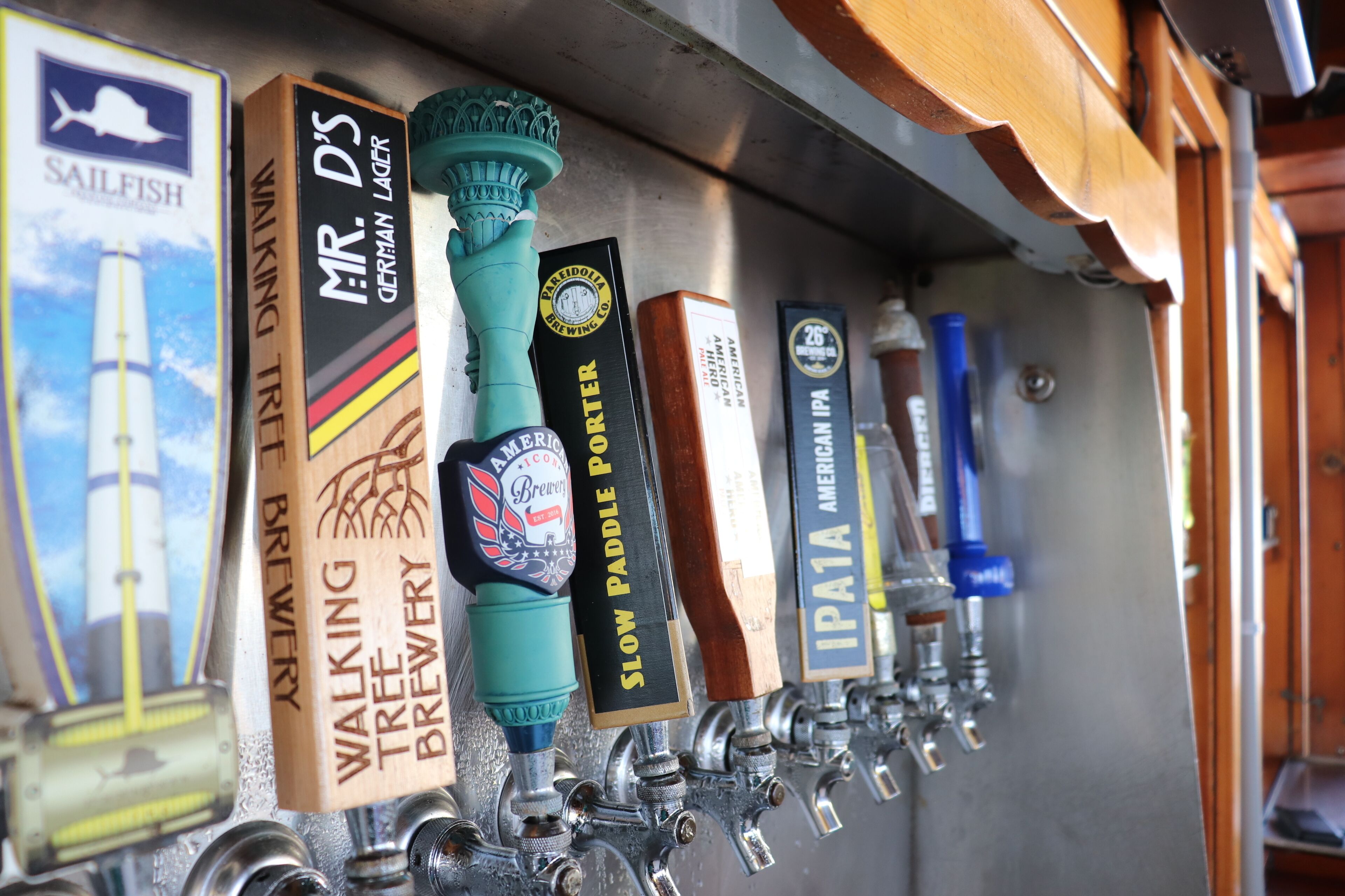 Una hilera de grifos de cerveza con etiquetas como "Walking Tree Brewery" y "Mr. D's German Lager".