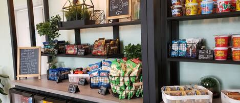 A coffee shop counter with various food items, drinks, and a chalkboard menu.