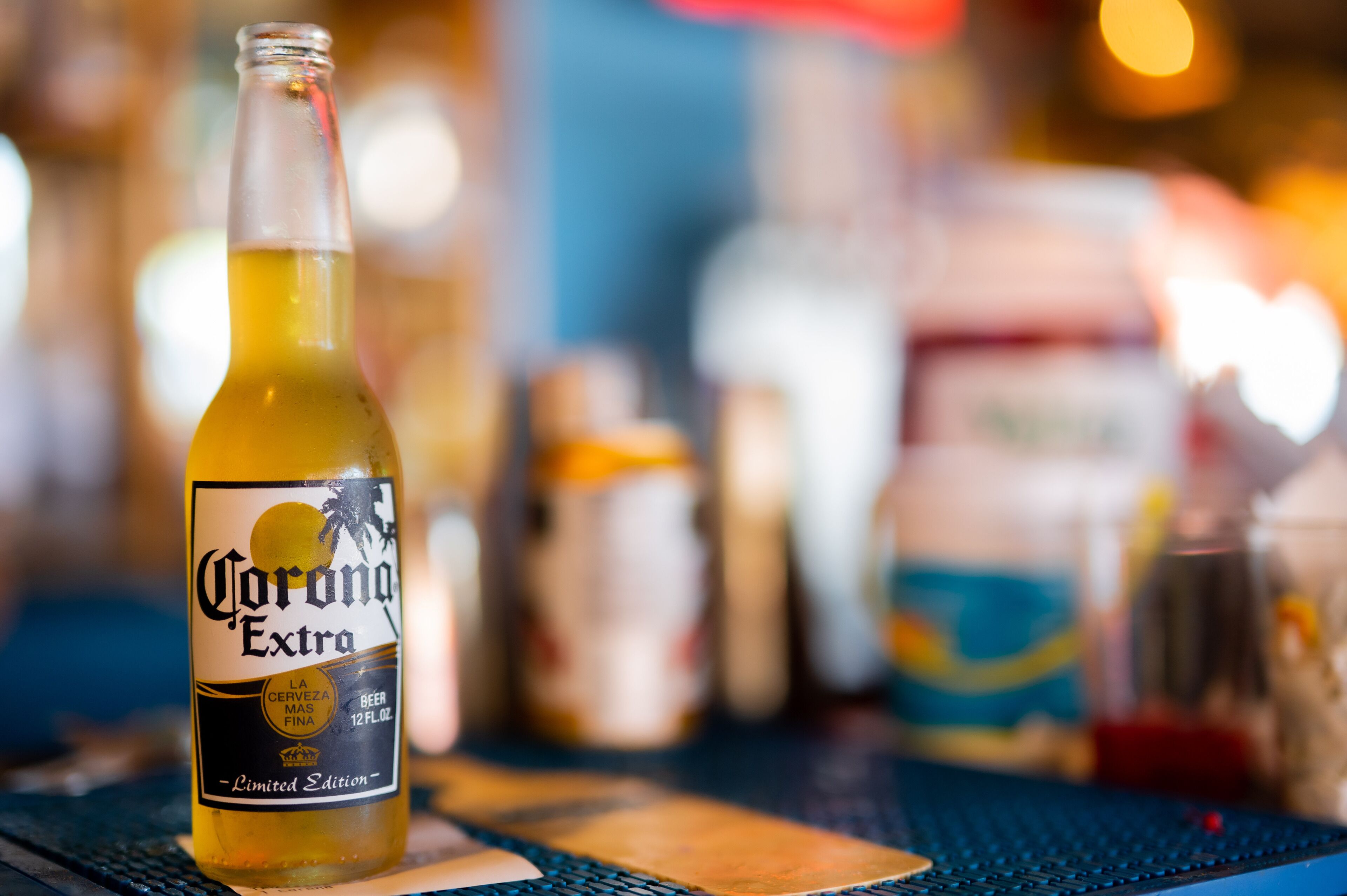A bottle of Corona Extra beer on a table with a blurred background.