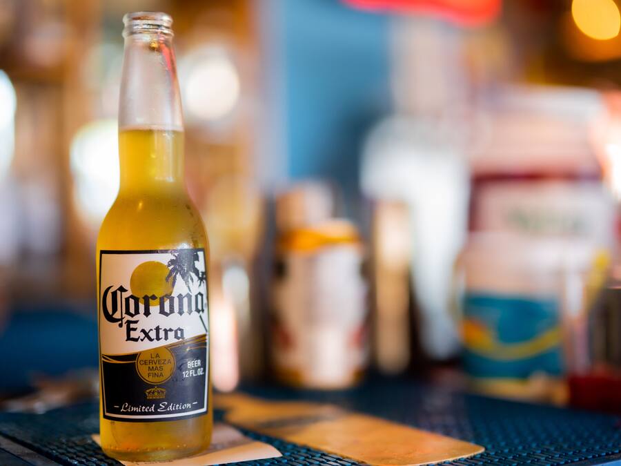 Een fles Corona Extra bier op een tafel, met een onscherpe achtergrond.