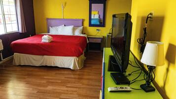 A hotel room with a bed, a television, a lamp, and a remote control on a green table.