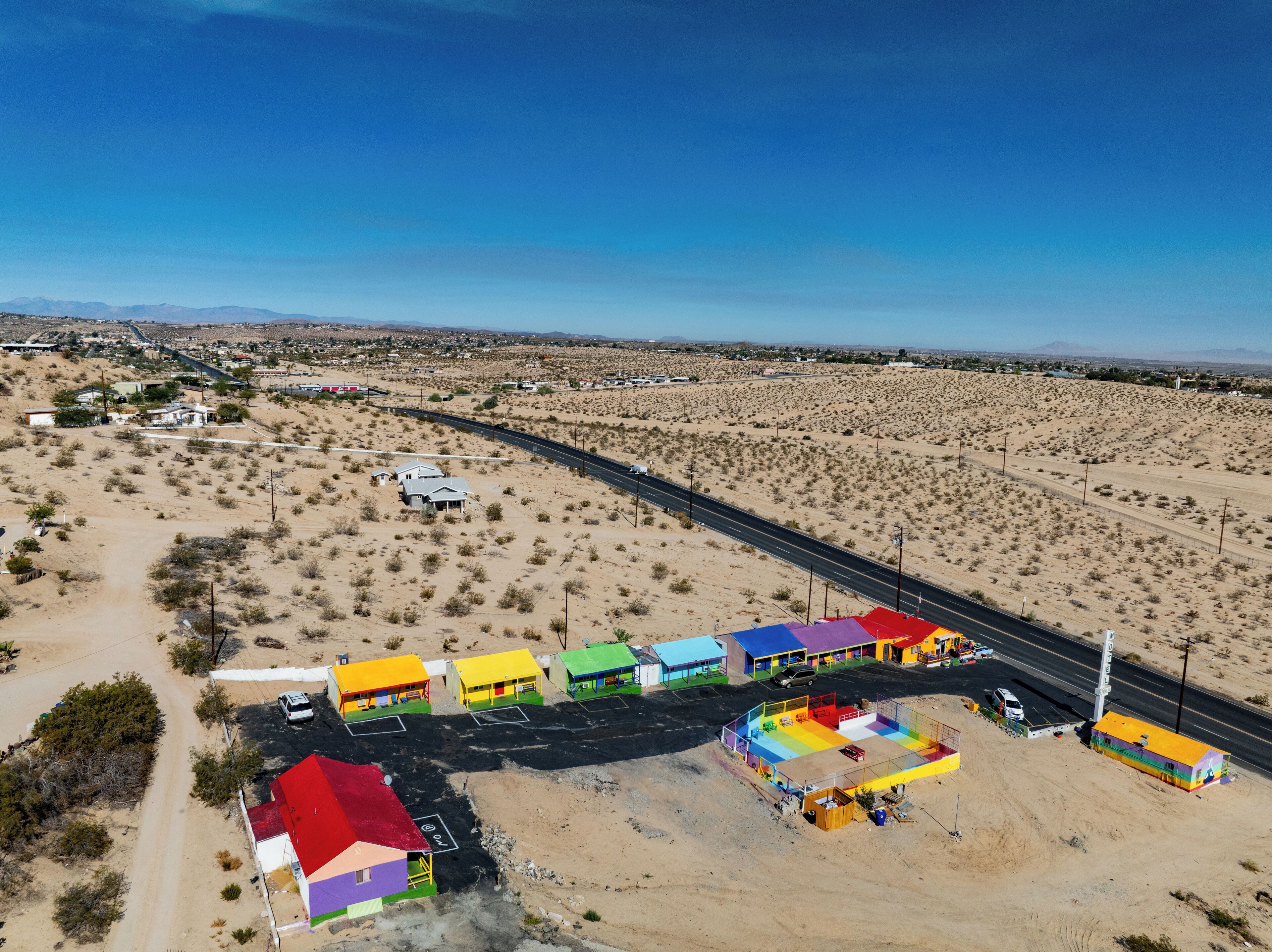 Vista aérea de una zona desértica con una carretera y un complejo de edificios coloridos.