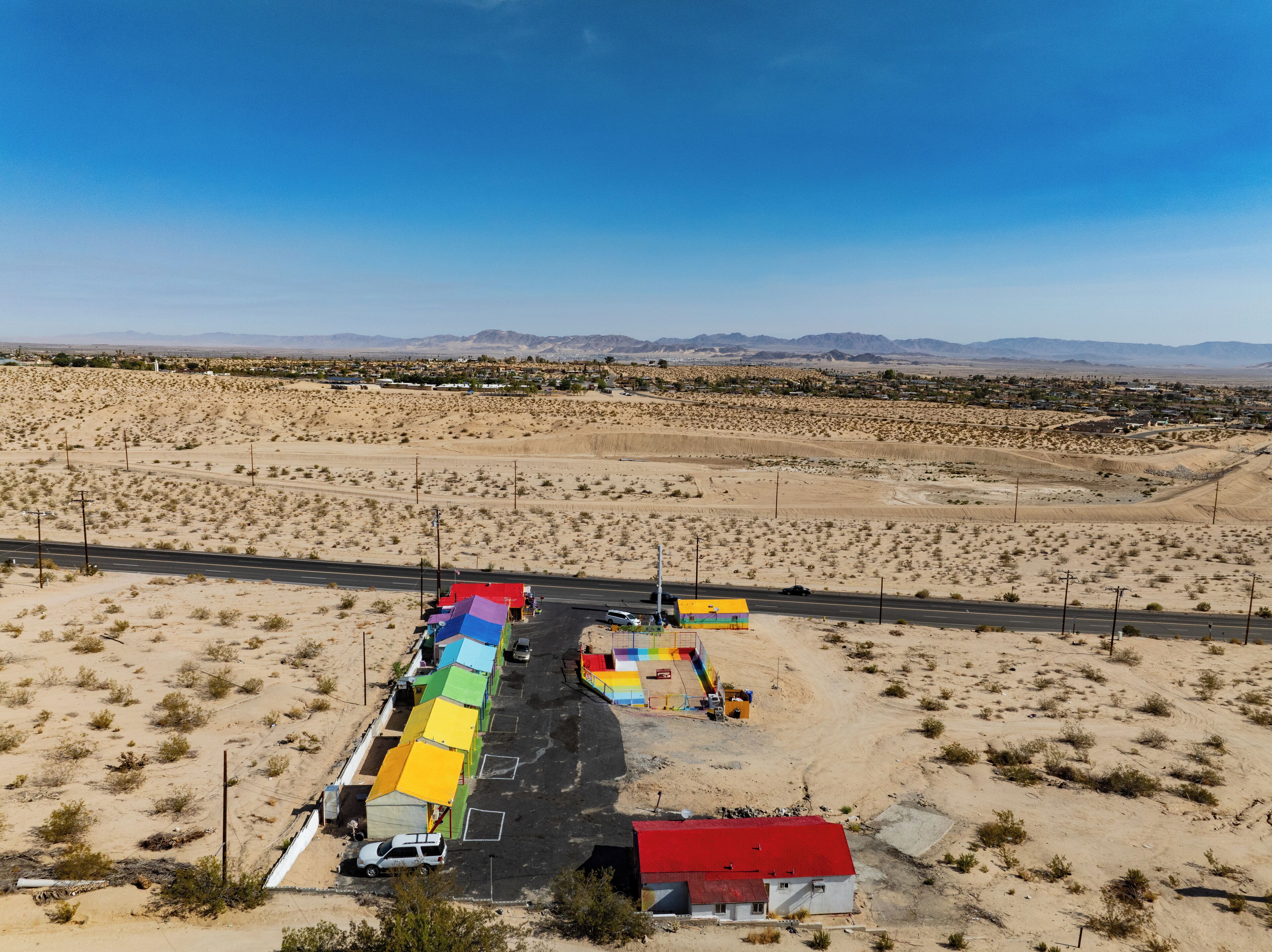 Un paysage désertique avec une route, des tentes colorées et un petit bâtiment.