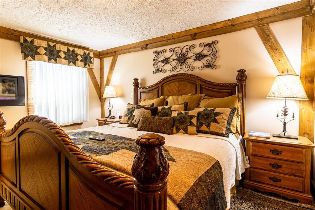 A cozy bedroom with a wooden bed, decorative pillows, a nightstand with a lamp, and a wall-mounted star decoration.