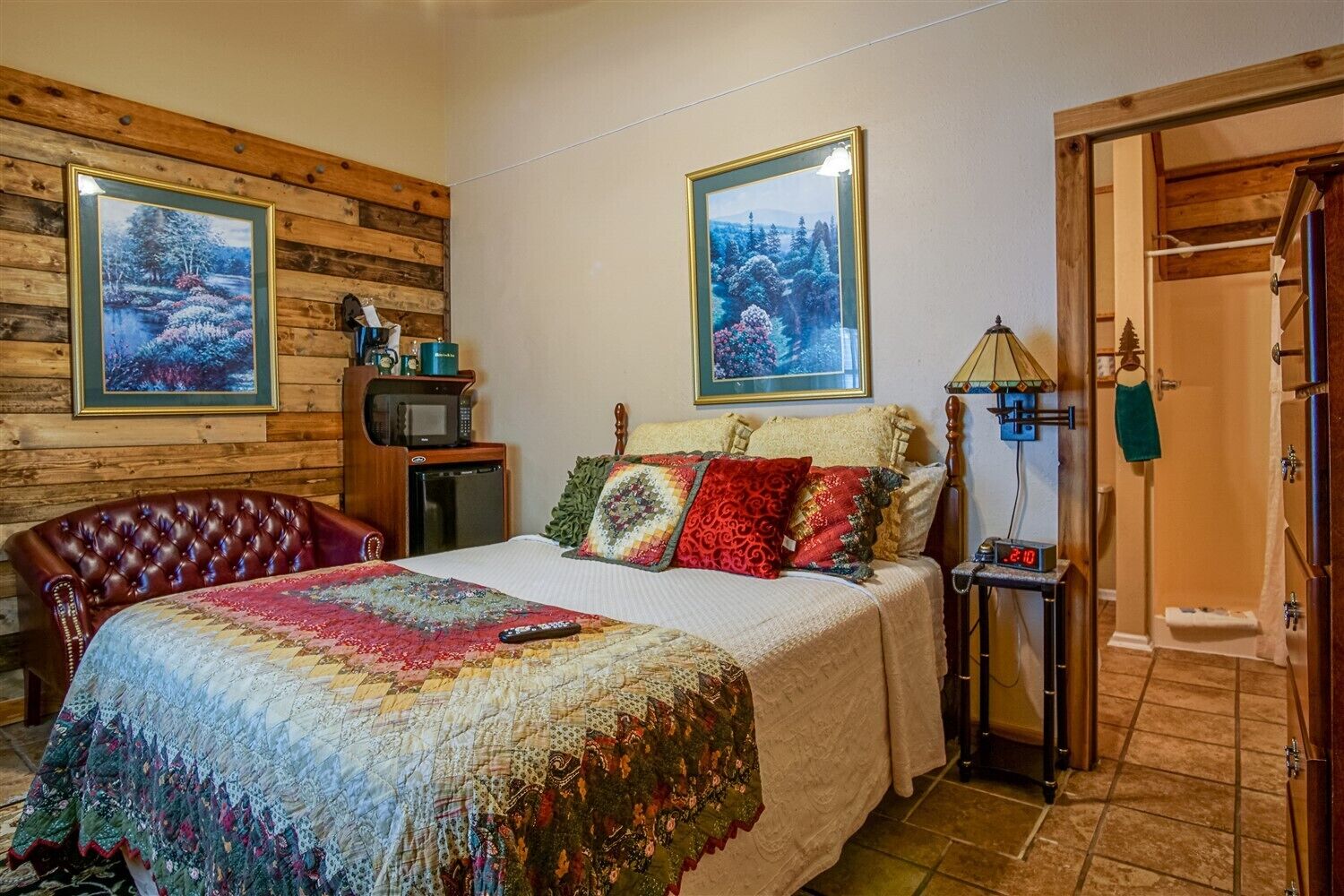 Un dormitorio acogedor con una cama grande, paredes de madera y dos cuadros de paisajes.