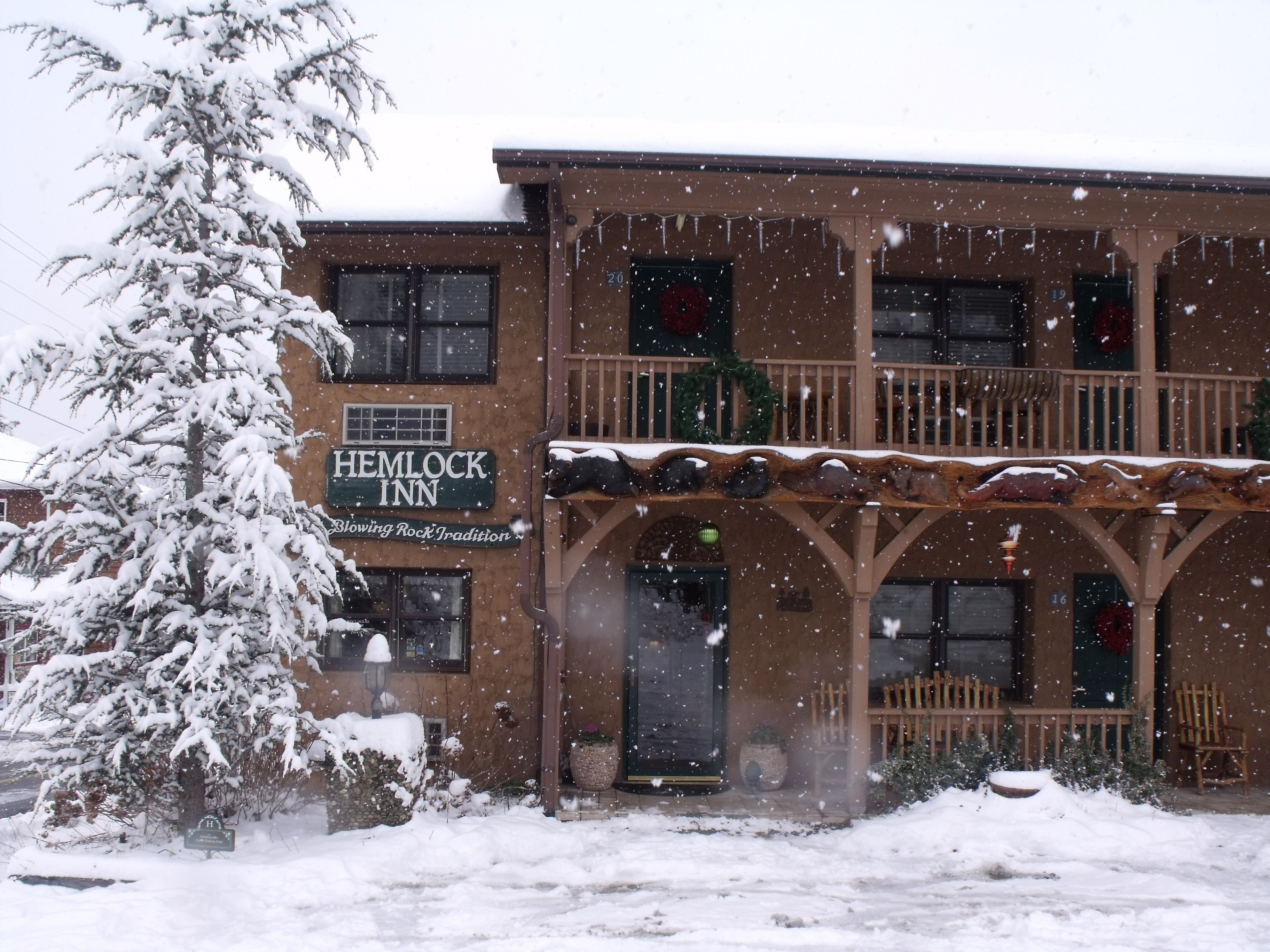 A Hemlock Inn with a traditional wooden facade, multiple windows, and a snow-covered entrance.