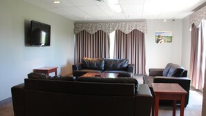 A living room with a black leather sofa, a wooden coffee table, and a television mounted on the wall. - Glendenning Hall (Charlottetown)