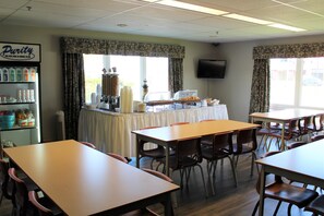 Un área de comedor con mesas y sillas, una estación de bufé con alimentos, y un letrero que dice "Purity".