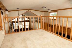 A room with a high ceiling, wooden beams, and a view of a loft area. - Sun Retreats New Point  (New Point)