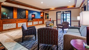 A lobby with a reception desk, patterned chairs, a sofa, and a small table with a laptop. - Best Western Jacksonville Inn (Jacksonville)