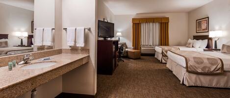 Ein Hotelzimmer mit Bad, Fernseher, Schreibtisch, Stuhl, Sofa und zwei Betten.