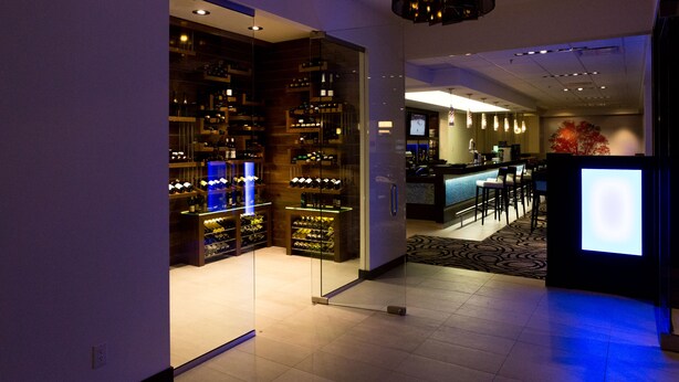 A modern hotel lobby with a wine cellar, a bar area, and a seating space. - The Grand Winnipeg Airport Hotel by Lakeview (Winnipeg)