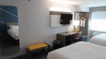 A hotel room with a bed, a desk, a chair, a TV, and a window.