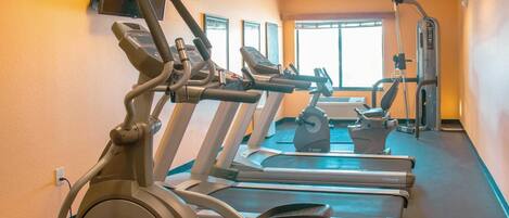 A gym with treadmills, stationary bikes, and a rowing machine.