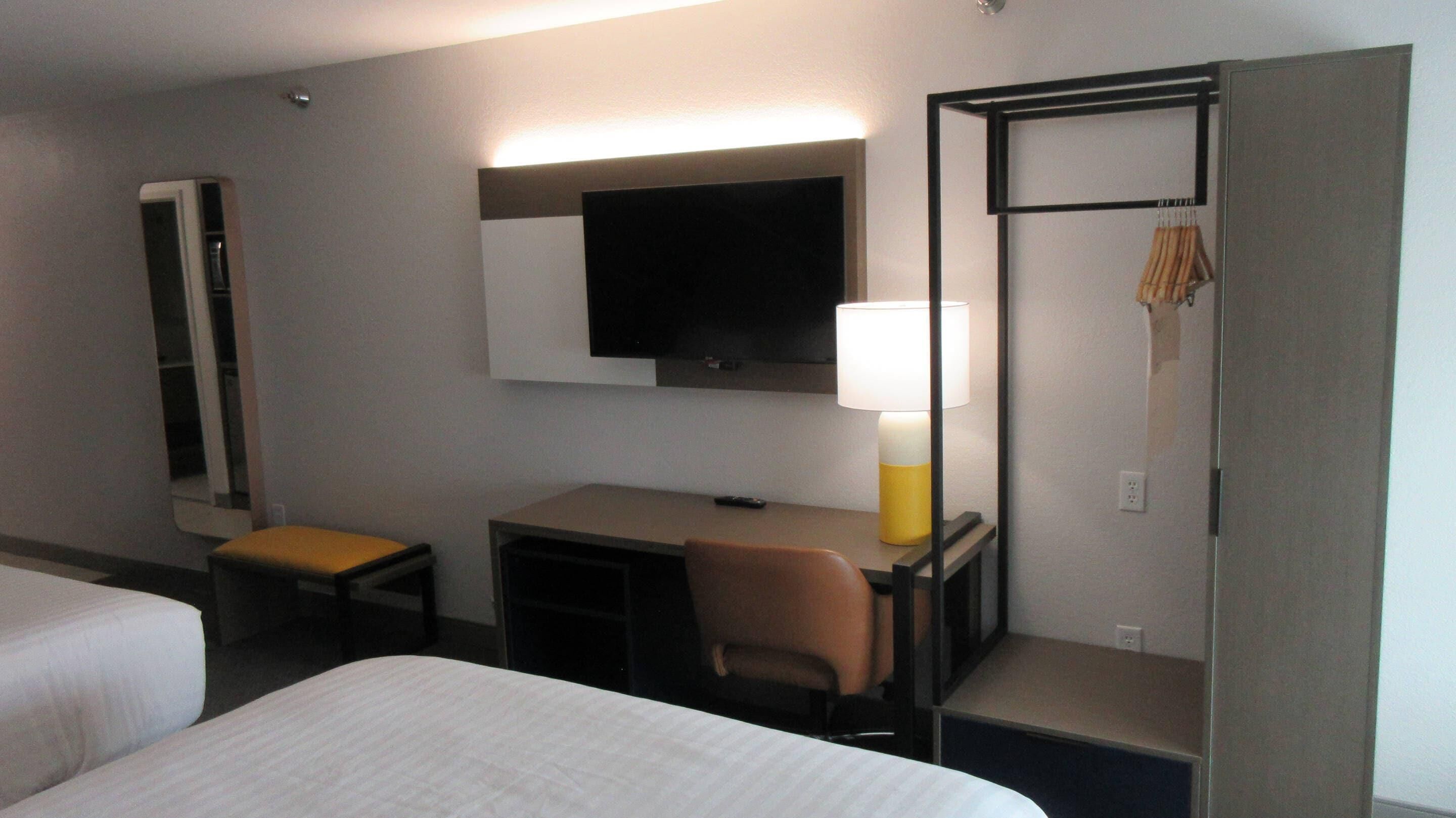 Une chambre d’hôtel équipée d’un lit, d’un bureau, d’une chaise, d’une télévision et d’une armoire.