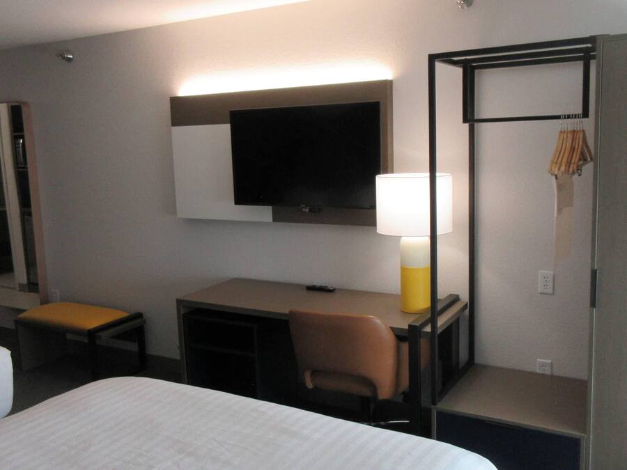 A hotel room with a bed, a desk, a chair, a television, and a wardrobe.