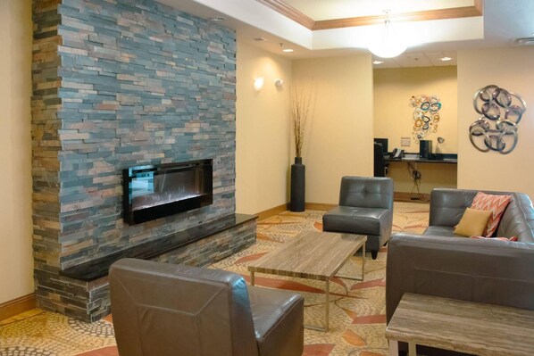 A lobby with a stone wall, a flat-screen TV, leather seating, and a reception desk. - Comfort Inn & Suites Grand Forks near Alerus Center (Grand Forks)