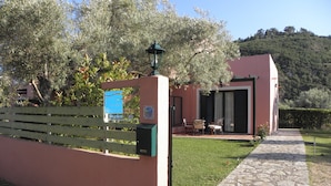 A property with a stone pathway leading to a modern building with a glass door and a patio area. - Ionian Breeze Studios (Lefkada)