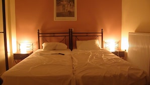 A double bed with white linens, two bedside tables with lamps, and a framed picture on the wall. - Ionian Breeze Studios (Lefkada)