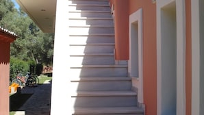 A staircase leading to a building with a pink exterior and white trim. - Ionian Breeze Studios (Lefkada)