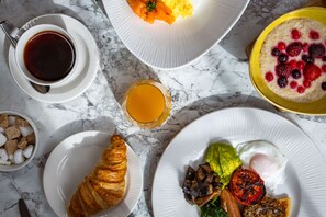 Ein Frühstückstisch mit verschiedenen Speisen, darunter ein Croissant, Eier und eine Schale Obst.