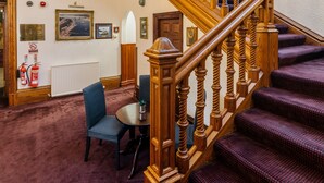 A grand staircase with wooden balusters and a red carpeted floor. - Lochardil House Hotel (Inverness)