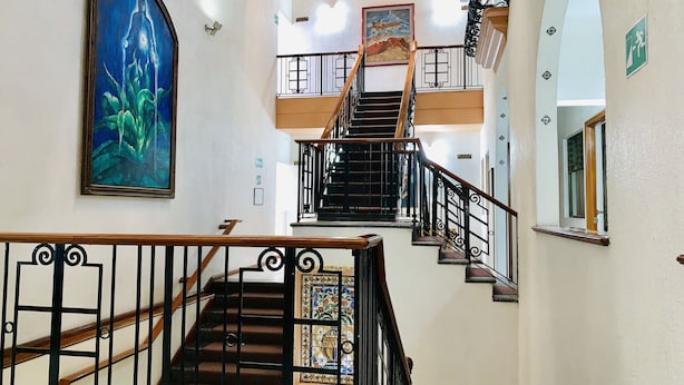 A multi-level interior with a staircase, a large framed painting, and a stained glass window.