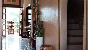 A spacious lobby with a tiled floor, a wooden tree stump, a potted plant, and a staircase leading to an upper level. - Hotel La Escalinata (Copan Ruinas)
