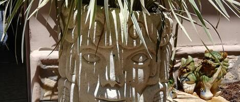 A stone planter with a carved face, a potted plant, and a small statue.