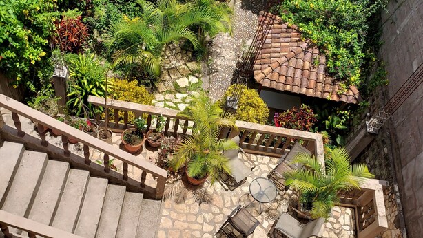 A stone-paved courtyard with a wooden staircase, potted plants, and outdoor seating. - Hotel La Escalinata (Copan Ruinas)