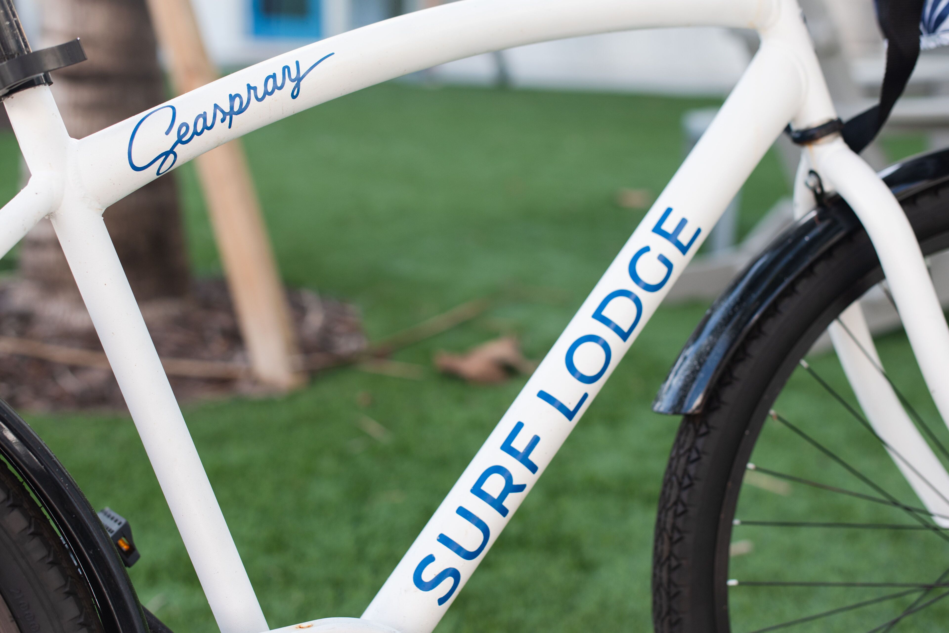 A white bicycle with "SURF LODGE" and "Seaspray" written on it.