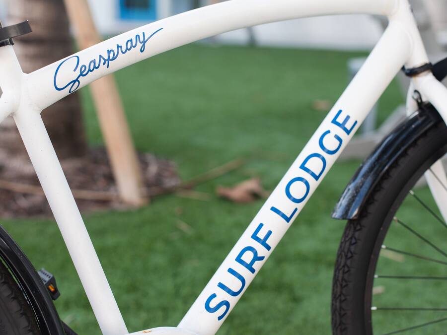 Una bicicleta blanca con la leyenda 'SURF LODGE' y 'Seaspray'.