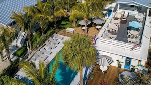 A resort with a pool, outdoor seating, and palm trees. - Seaspray Surf Lodge (Vero Beach)