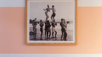 A framed photograph of a beach scene with people standing on a surfboard.