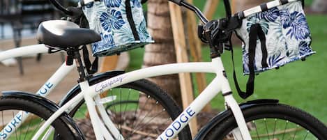 Un vélo blanc, équipé d’un panier et d’un sac, est garé sur l’herbe.