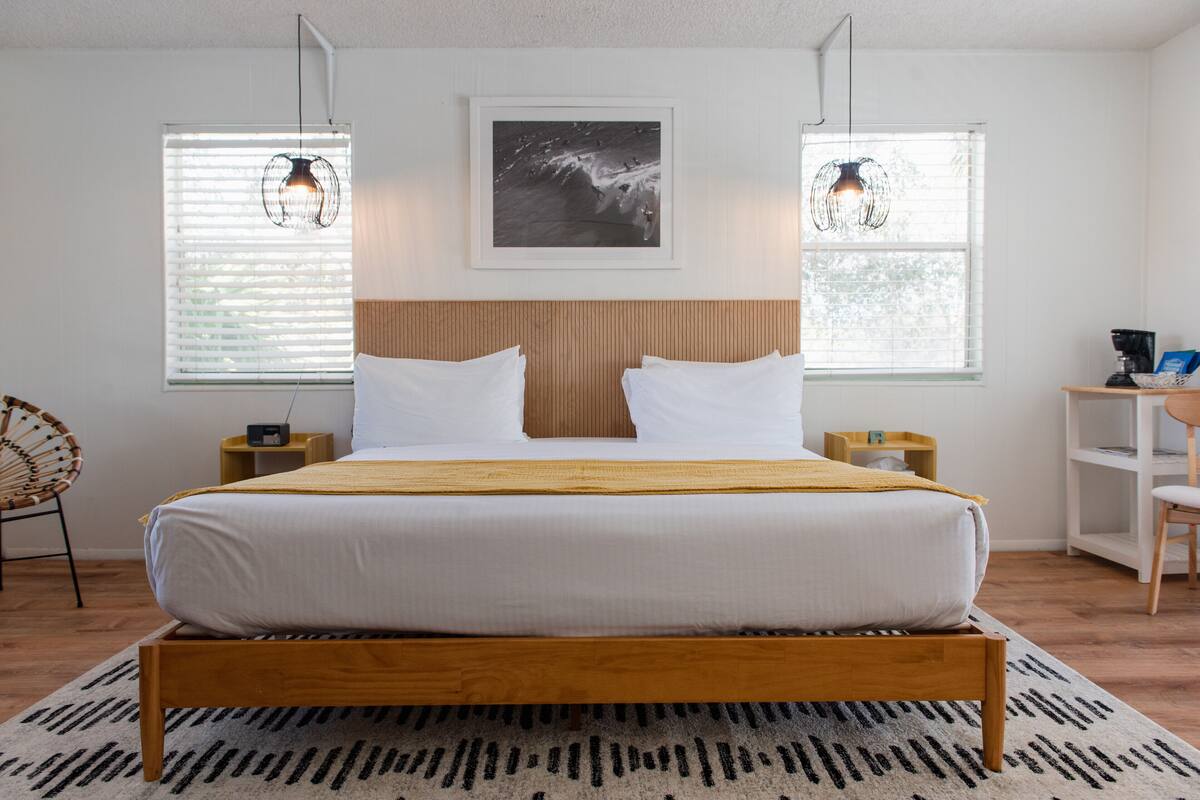 A modern bedroom with a wooden bed, white bedding, and two bedside tables with lamps.